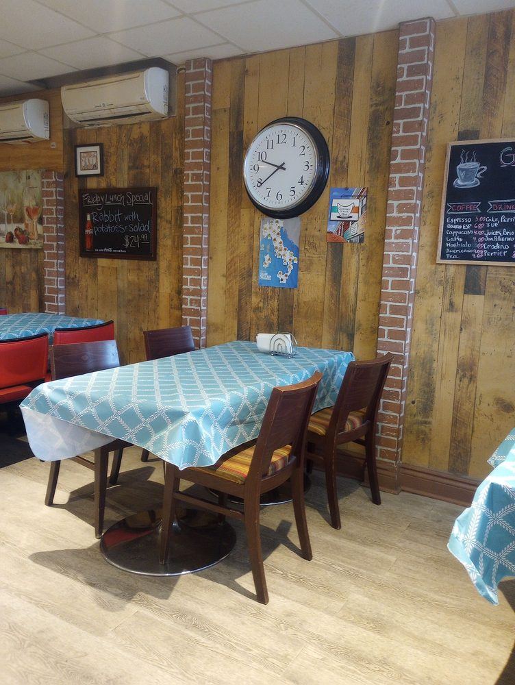 Dining room with checked tablecloths, a wall clock and wood-panelled wall